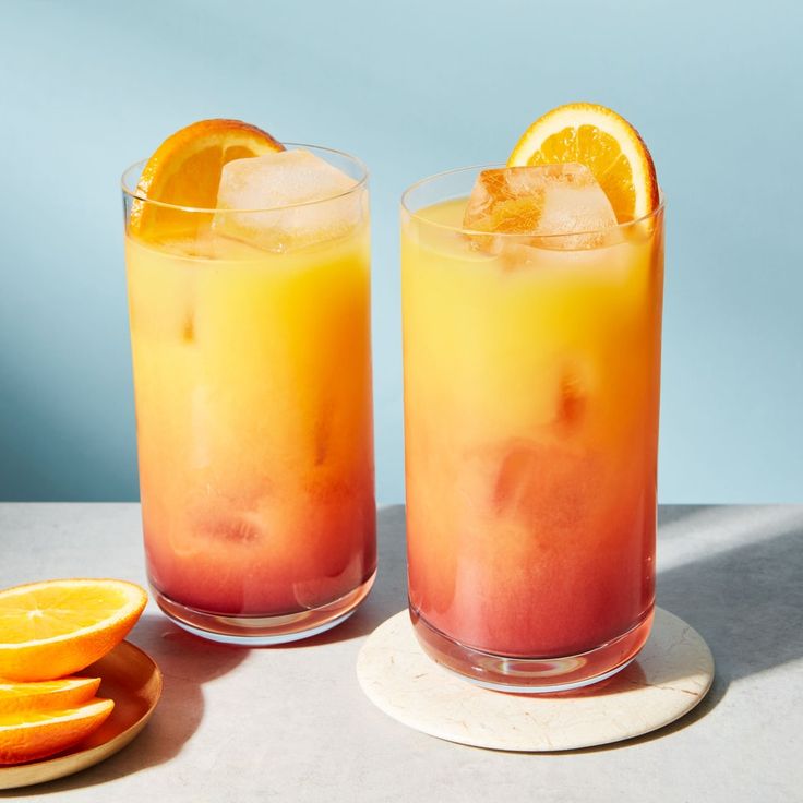 two glasses filled with orange juice on top of a table