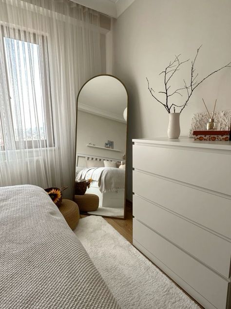 a bedroom with a bed, dresser and large mirror in the corner next to it