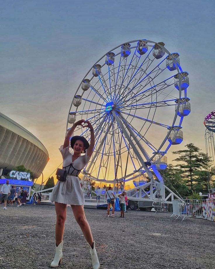 a woman standing in front of a ferris wheel