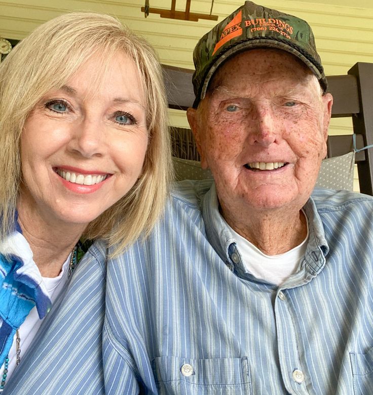 an older man and woman sitting next to each other in front of a porch chair