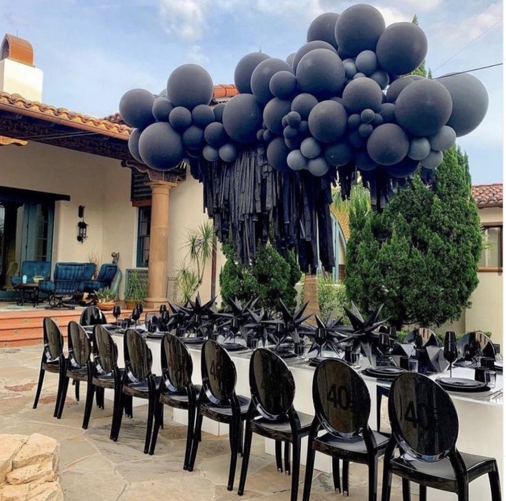 a table set up with black chairs and balloons