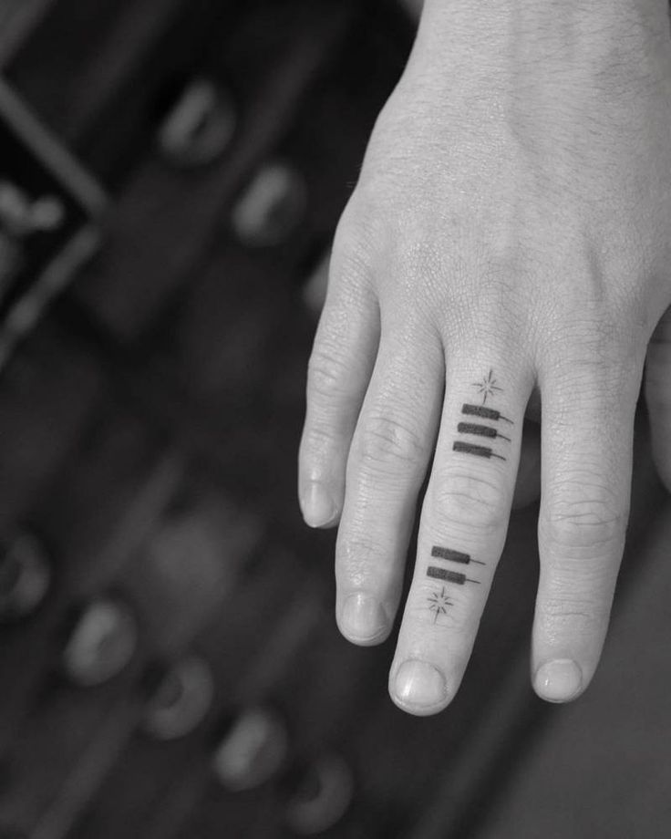 a person's hand with two small tattoos on their fingers and the other finger