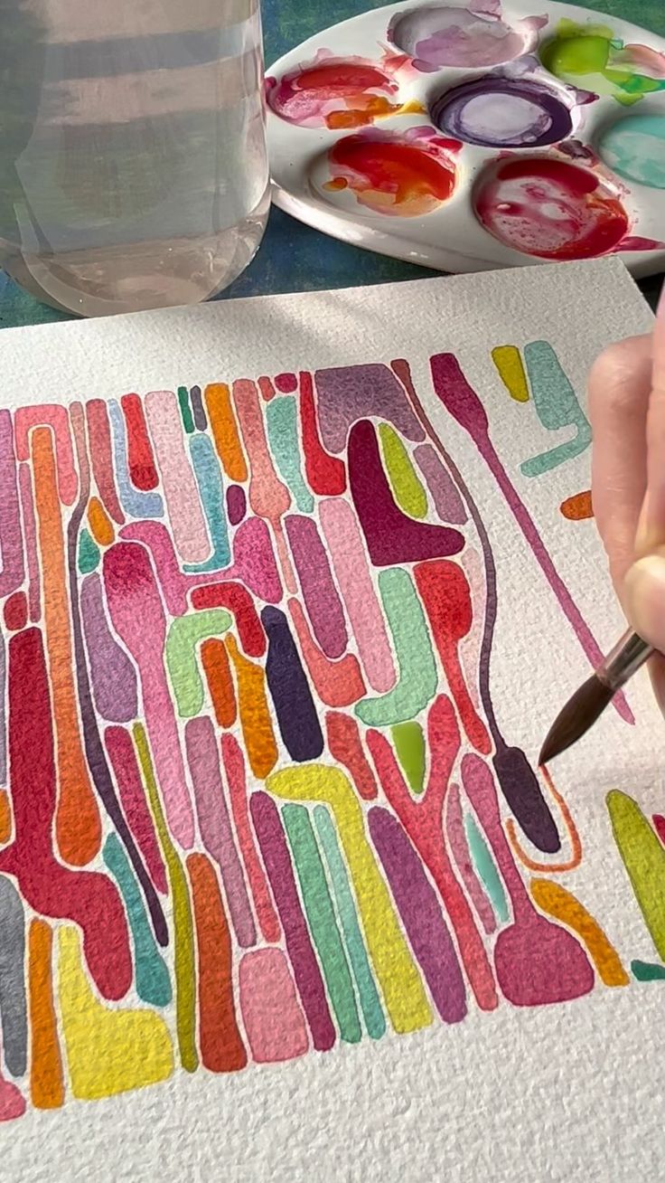 someone is painting on paper with watercolors