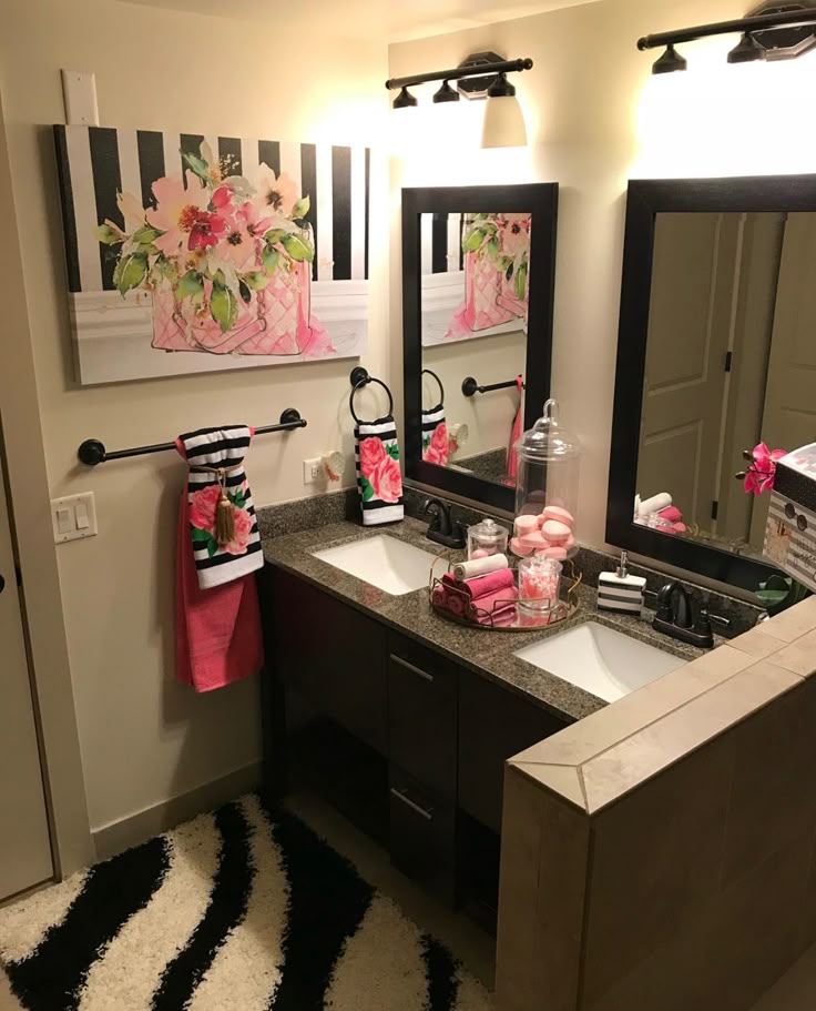 a bathroom decorated in pink and black with flowers on the towel rack, mirror, sink and toiletries