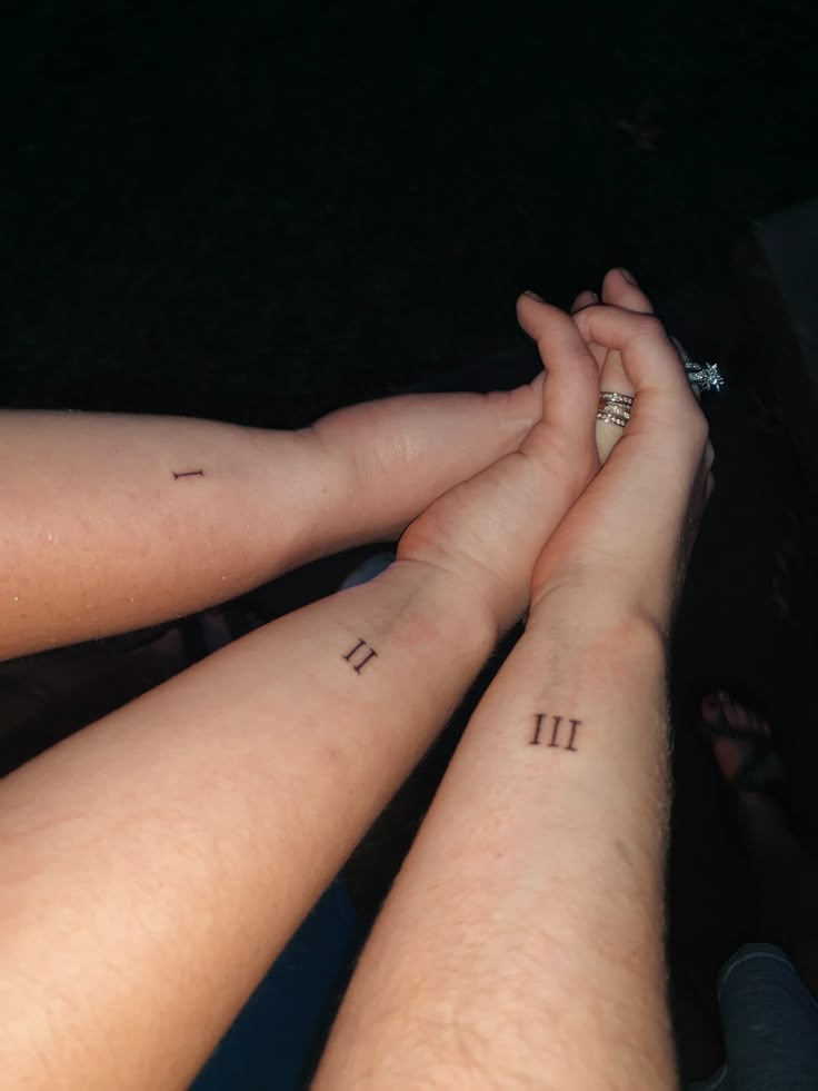 two people holding hands with numbers tattooed on them