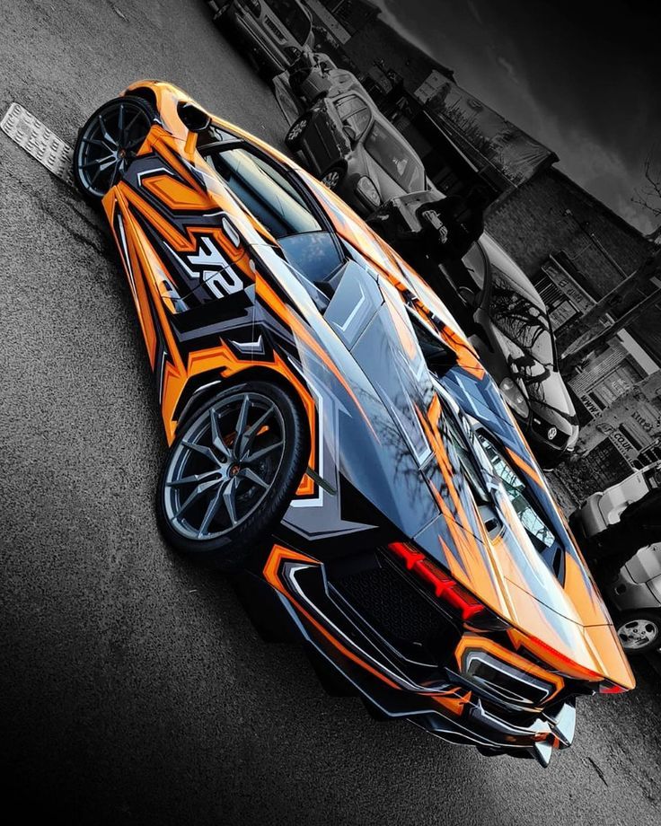 an orange and black sports car parked on the street