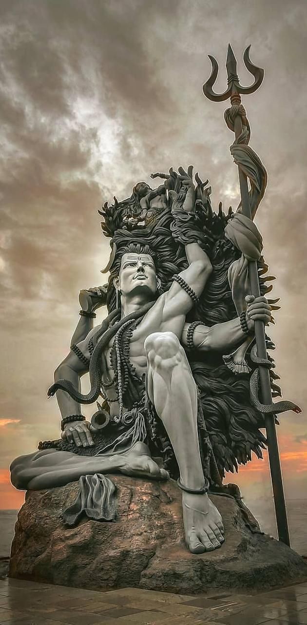 a statue sitting on top of a rock next to the ocean with a person holding a spear