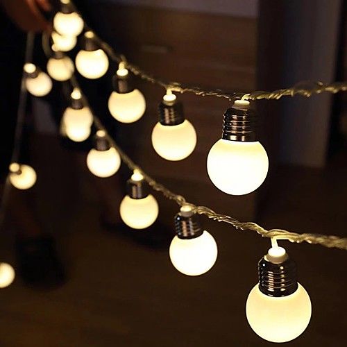 a string of light bulbs on a dark wood floor with one person standing next to it