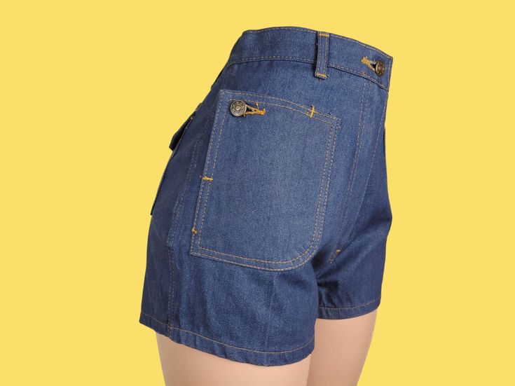 "Like new crisp dark wash twill denim shorts with a mid to high rise & short cut. To me, the fit is cute, but they're really all about the pockets! They're all flap patch pockets with buttons, but the 2 in front are so unique as the pocket can unbutton into a diagonal flap & are still accessible buttoned up. There are moderate belt loops & a robust metal zip fly with a button closure. The topstitching is burnt orange. ♡ LABELS & SIZING Made in the 70s in Thailand. There's not any branding anywhe Retro High Waist Relaxed Fit Jean Shorts, Fitted Denim Jean Shorts With Belt Loops, High Waist Cotton Jean Shorts With Belt Loops, Retro Short Relaxed Fit Jeans, Medium Wash Jean Shorts With Hip Pockets, Fitted Dark Wash Jean Shorts, High Rise Denim Shorts With Hip Pockets, Fitted High Rise Shorts With Hip Pockets, High Rise Fitted Shorts With Hip Pockets