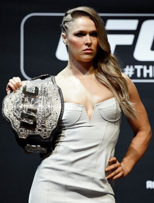 a woman in white dress holding a wrestling belt