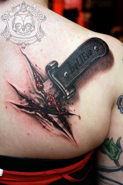 a woman's shoulder with a knife and blood splattered tattoo on it