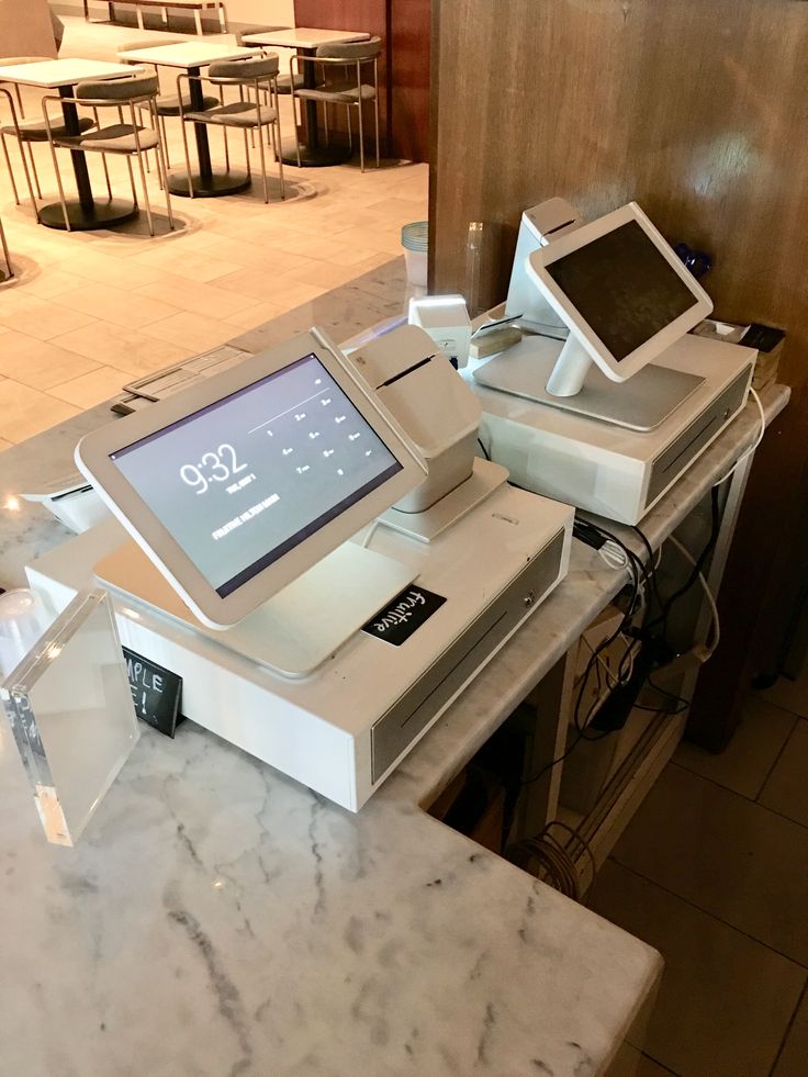 an electronic device sitting on top of a counter in a room filled with tables and chairs