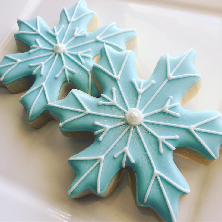 two decorated cookies sitting on top of a white plate covered in frosted icing