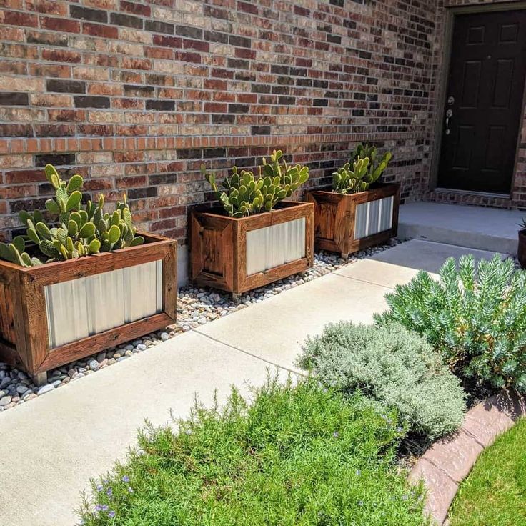 three wooden planters with succulents in front of a brick building