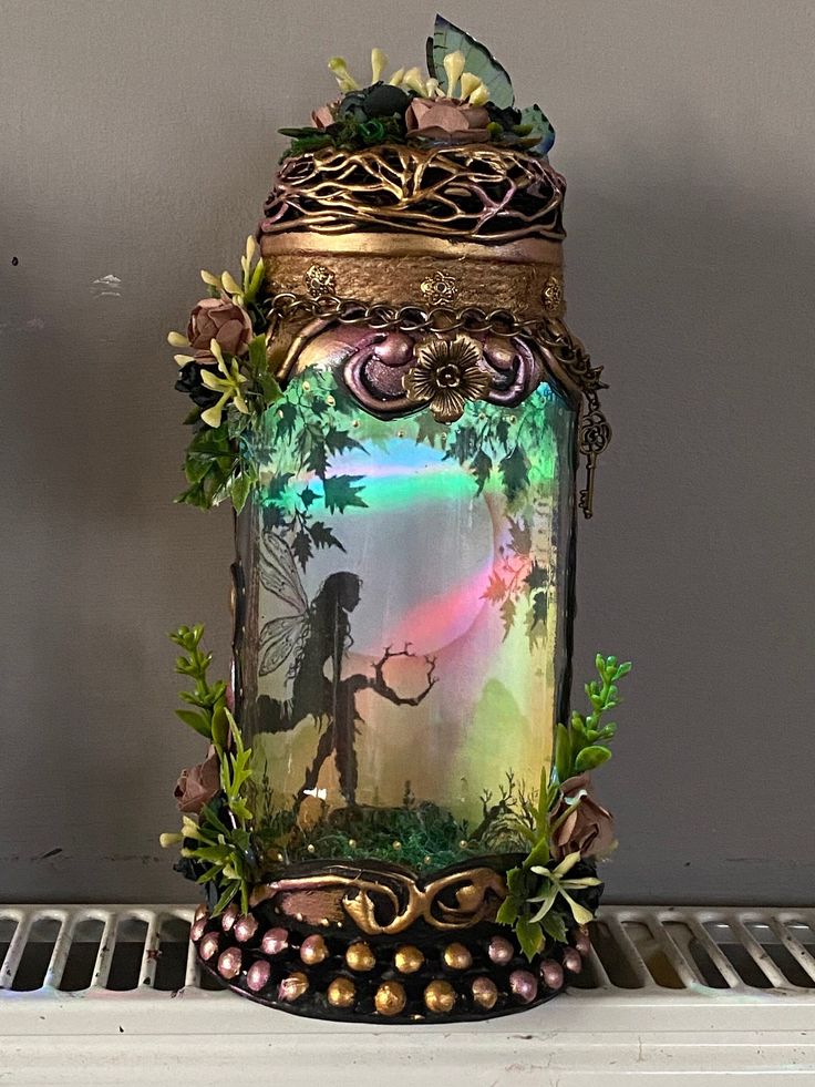 a glass jar with an image of a fairy holding a rainbow light in it's mouth