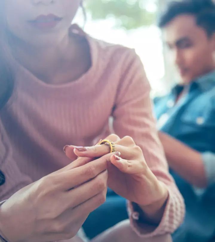 two people sitting on a couch looking at their cell phones while one person holds the other's hand