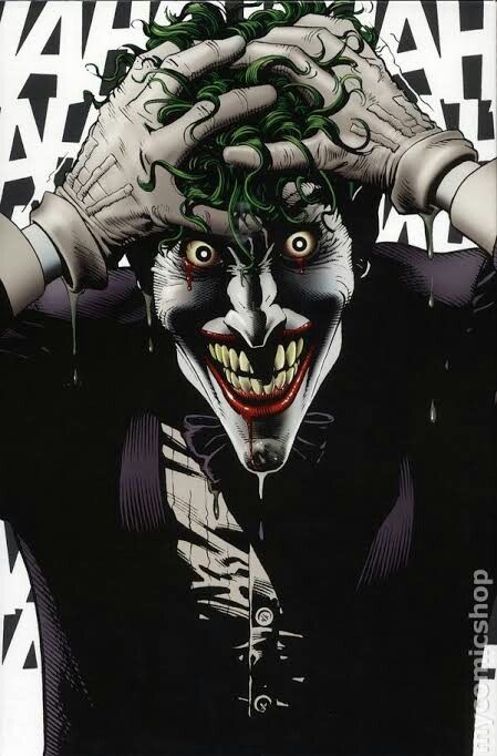 the joker with his hands on his head and green hair, wearing a black suit