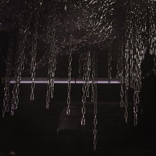 rain drops falling down from the ceiling in front of a window at night with black and white background