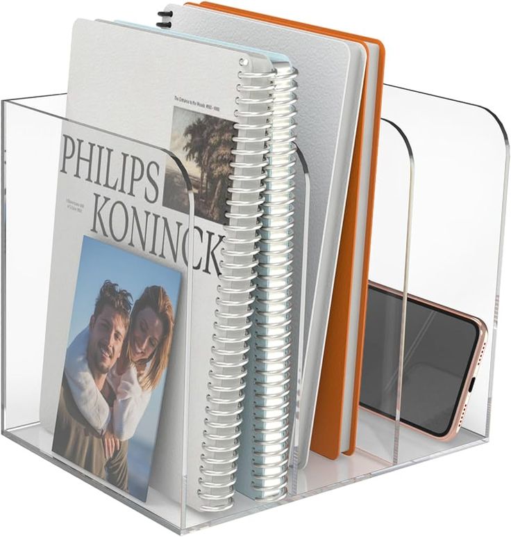 a clear book holder holds two magazines and a cell phone