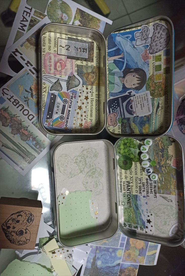 four tins filled with different types of papers and stickers on top of a table