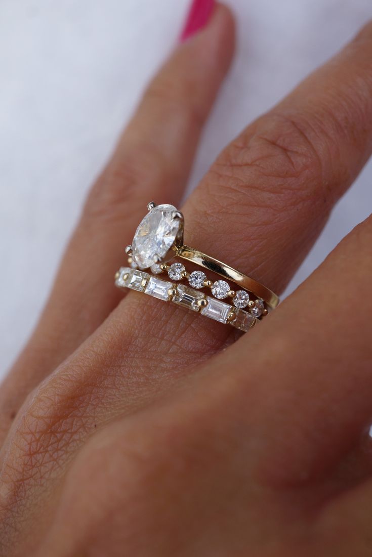 a woman's hand with a gold ring and two diamond rings on top of it