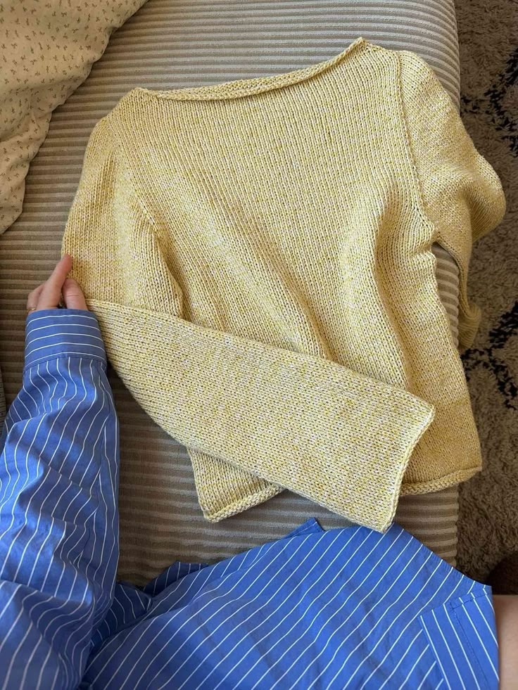 a person laying on top of a bed with a yellow sweater and blue pants next to each other