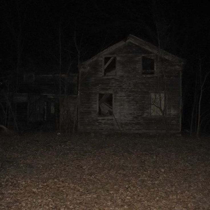 an old house in the woods at night with no one around it or someone standing outside