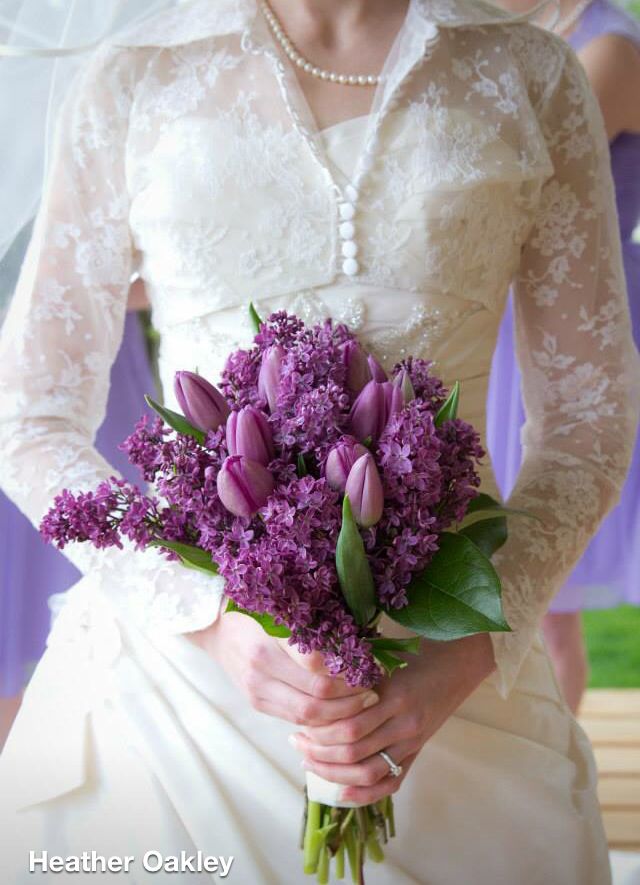 a bride holding a bouquet of purple flowers