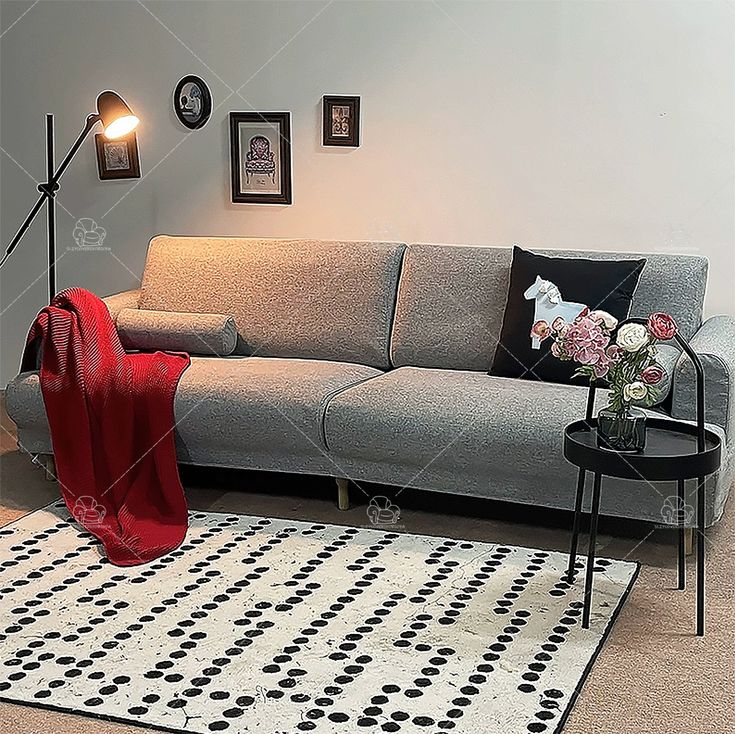 a living room with a gray couch and black table on top of the rug in front of it