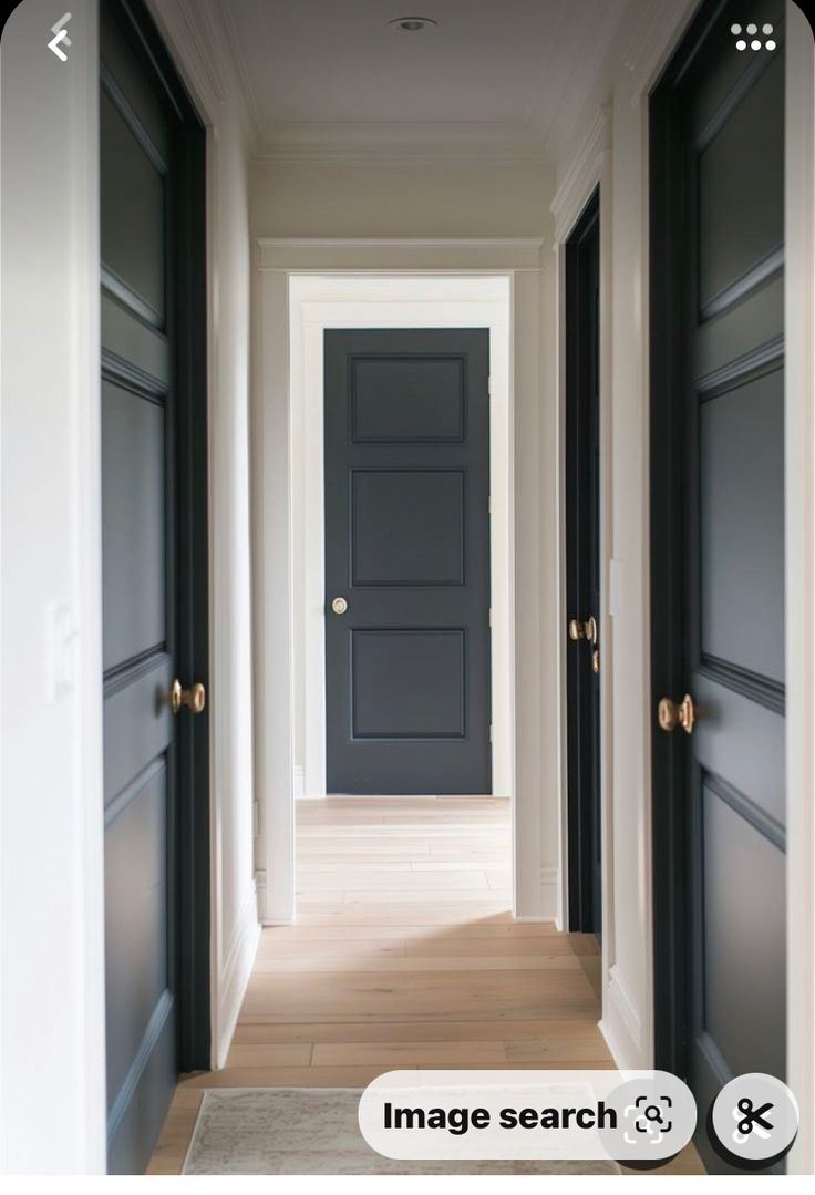 an empty hallway with black doors and white trim on the walls is seen in this image