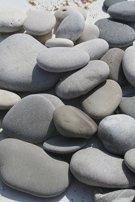 several gray and white rocks sitting on top of each other in the sand next to water