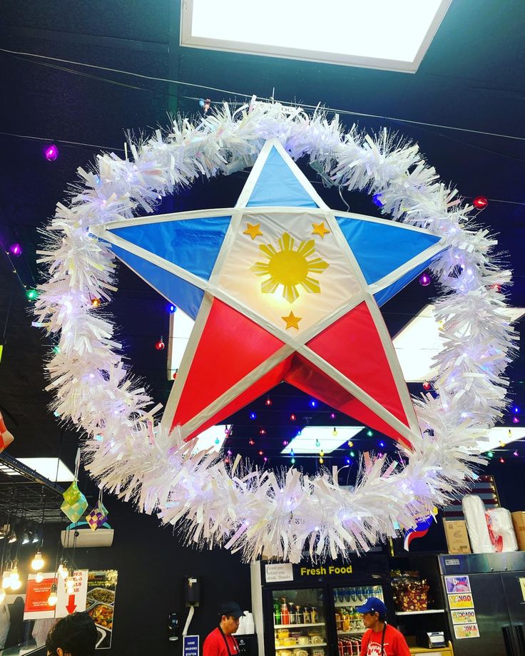 a red, white and blue star hanging from the ceiling in front of some people