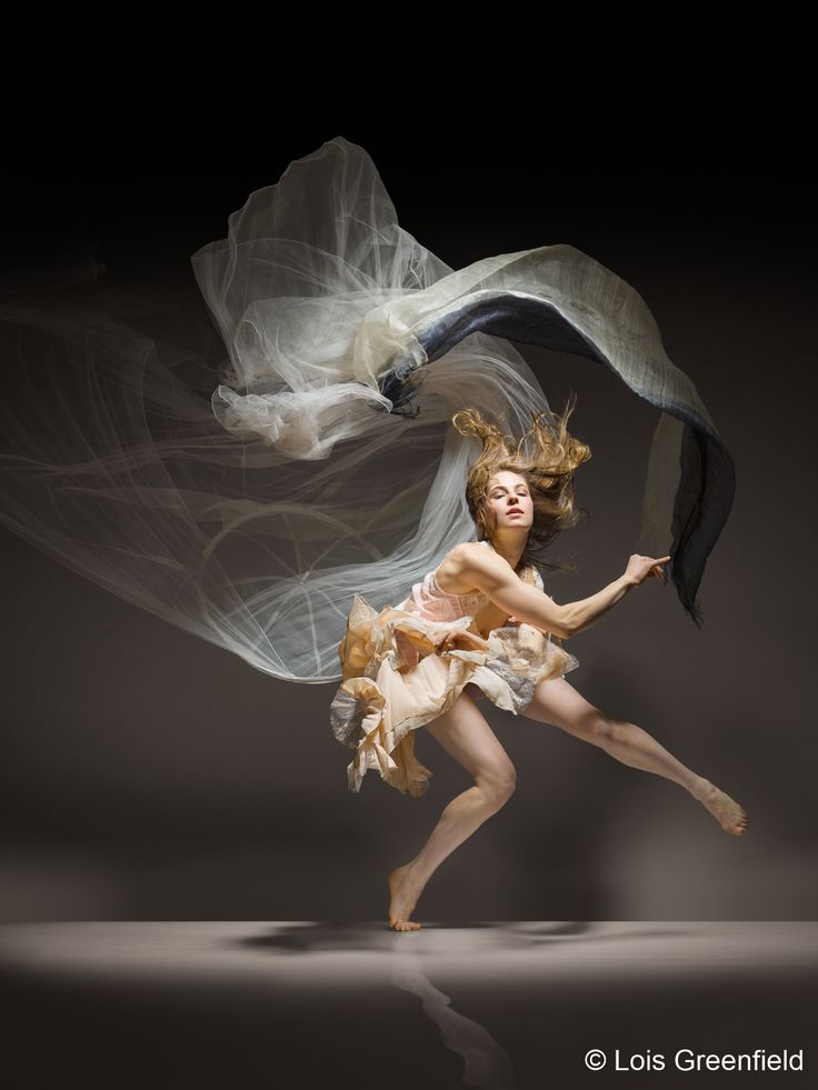 a woman is dancing with her hair blowing in the wind while wearing a white dress