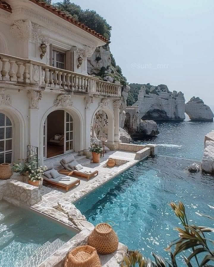 an outdoor swimming pool with chaise lounges next to the water and cliffs in the background