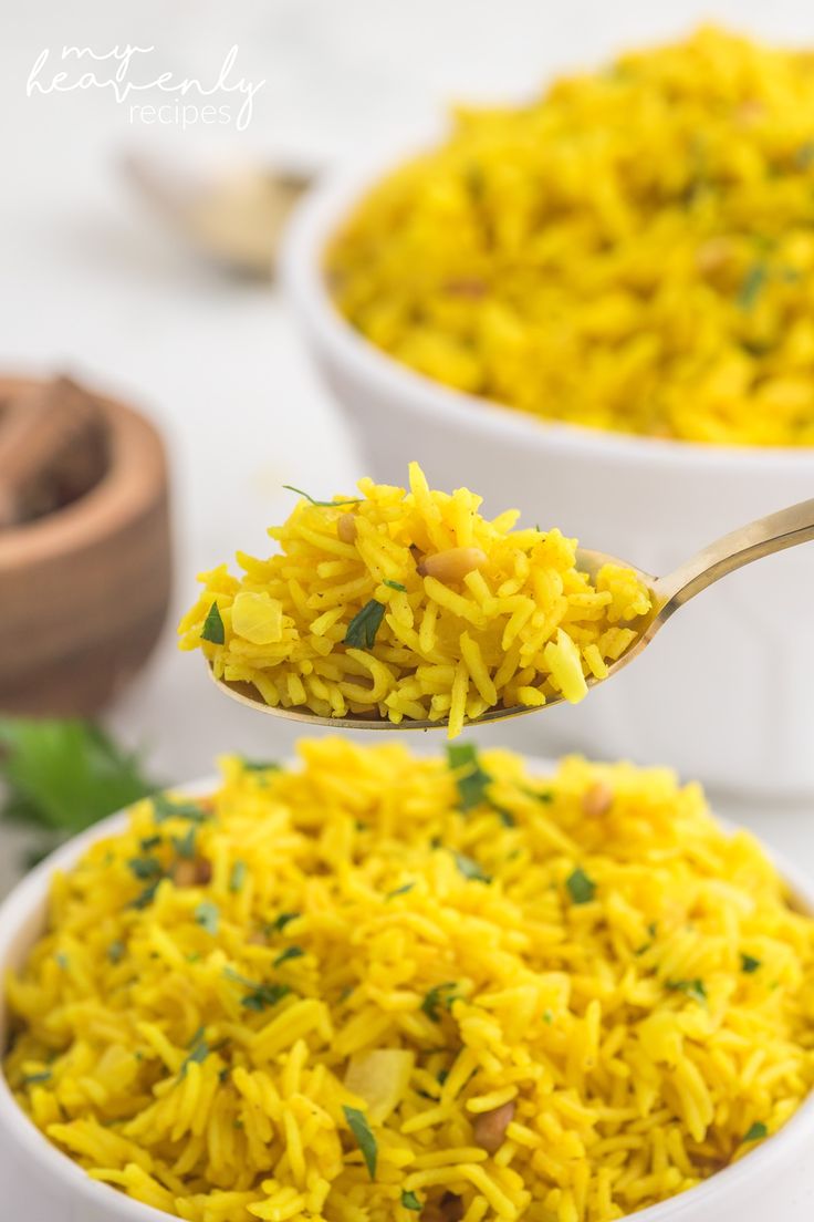 a spoon full of yellow rice with parsley on top and another bowl in the background