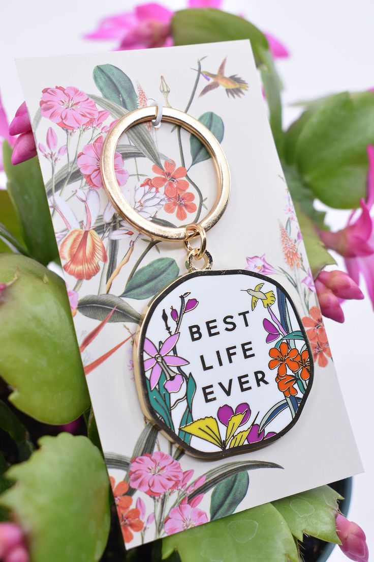 a keychain that says best life ever on it with flowers in the background