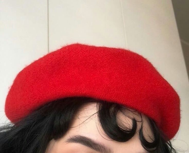 a close up of a person wearing a red hat with long black hair and bangs