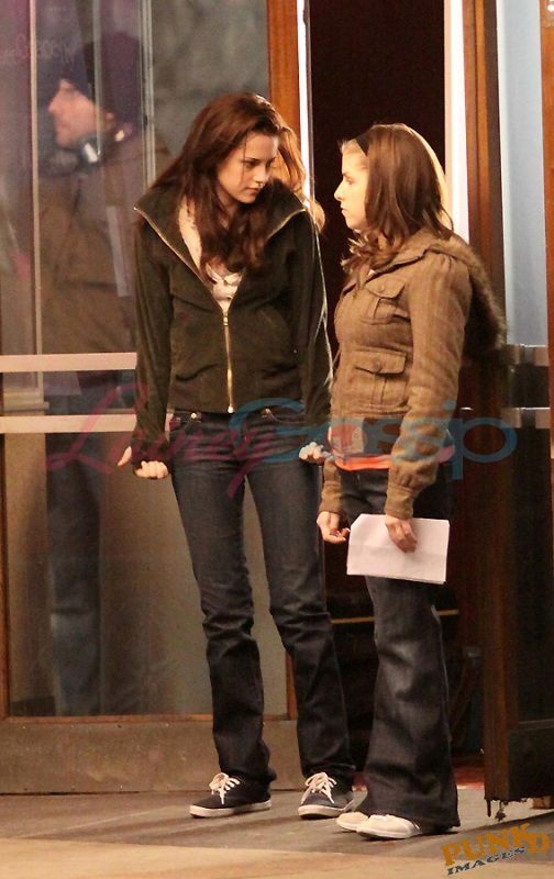 two young women standing next to each other in front of a building with glass doors