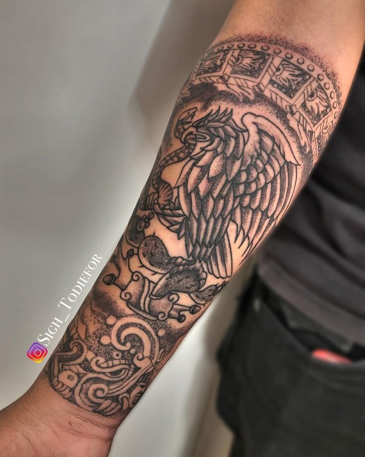 a man's arm with an eagle and cross tattoo on the left side of his arm