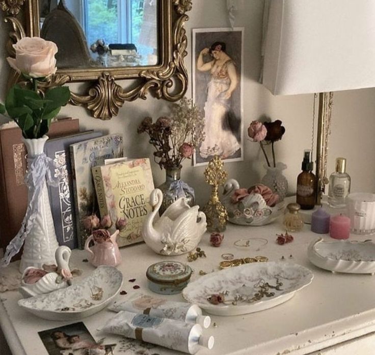 a white dresser topped with lots of clutter next to a mirror and vase filled with flowers