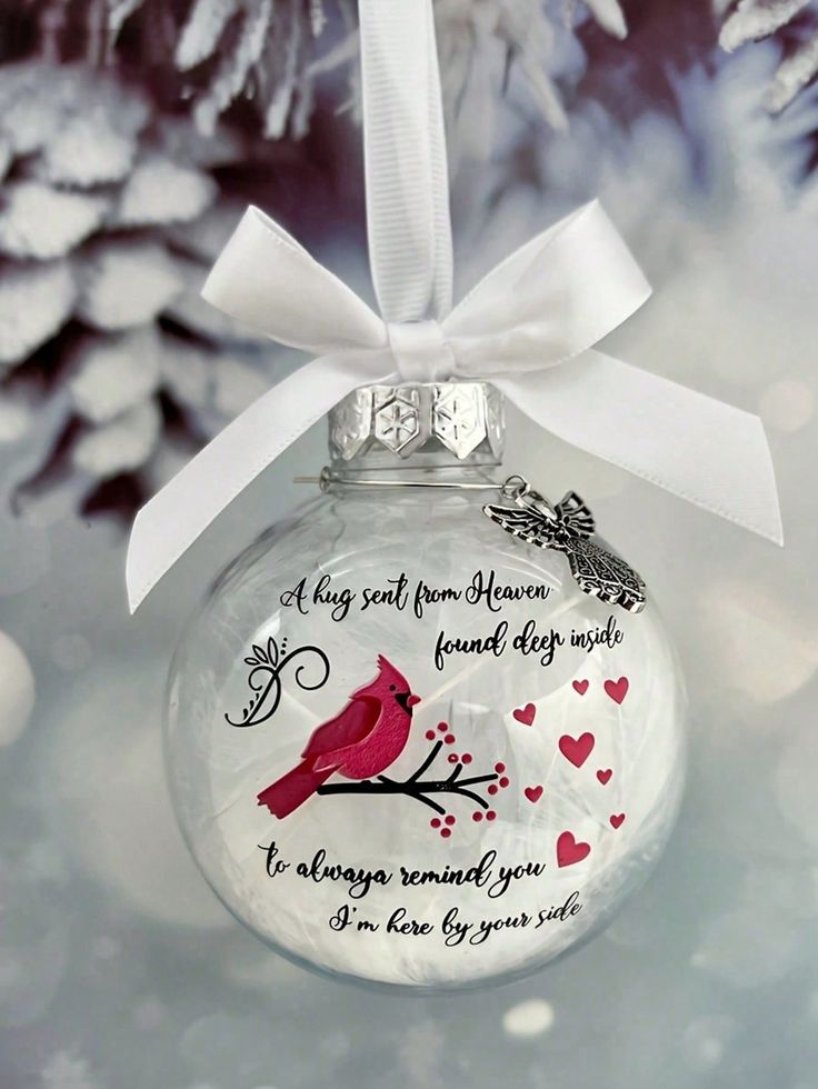 a glass ornament hanging from a christmas tree with a red bird on it