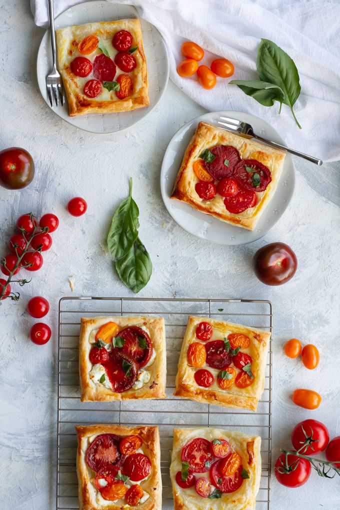 four square pizzas with tomatoes and basil on top, sitting on a cooling rack