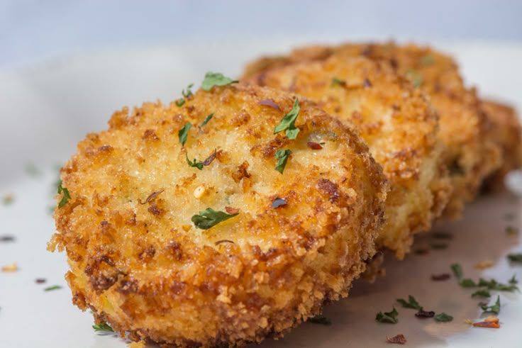 two fried chicken patties on a plate with parsley sprinkled on top