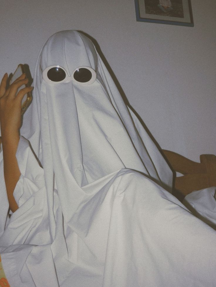 a person in a ghost costume holding a cell phone