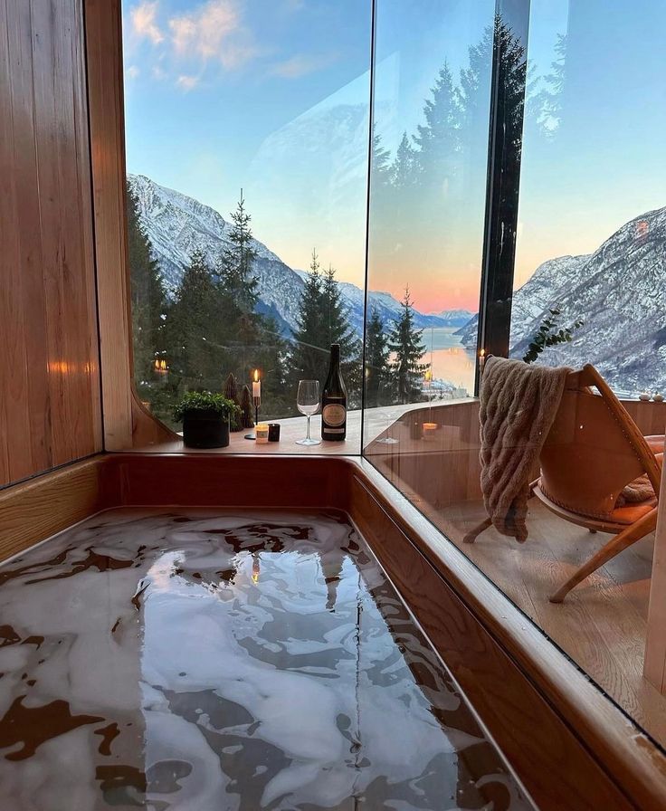 a hot tub in the middle of a room with a view of mountains and trees