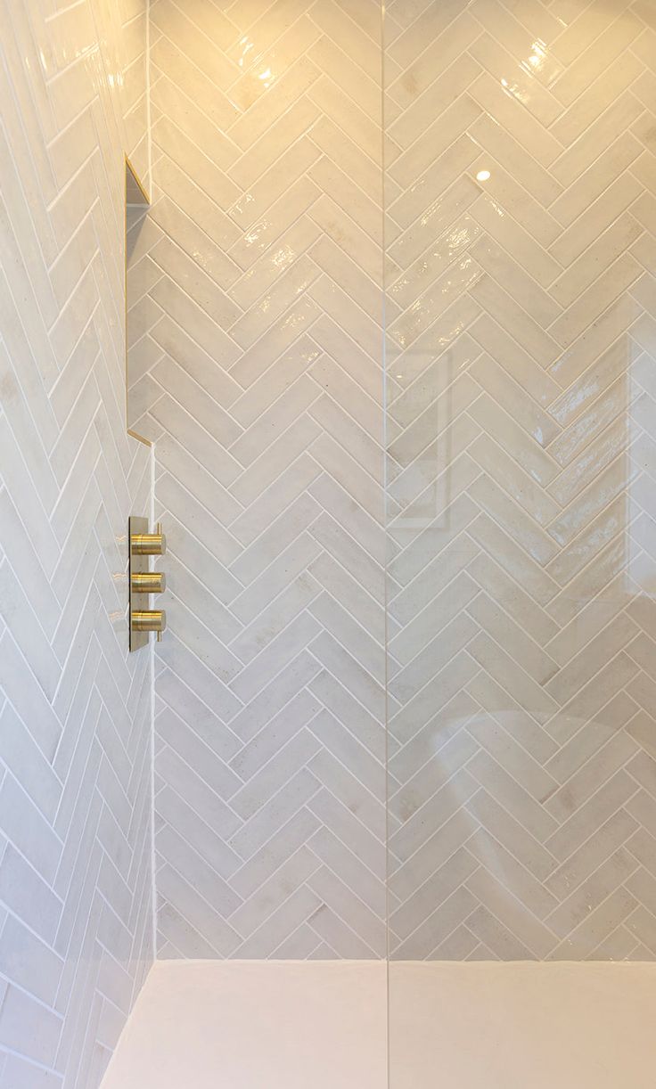 a shower with white tile and gold fixtures