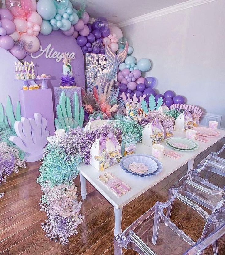 a table set up with balloons, cake and decorations for a mermaid themed birthday party