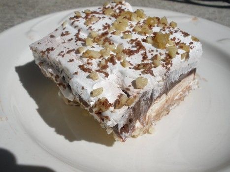 a white plate topped with a piece of cake covered in frosting and toppings