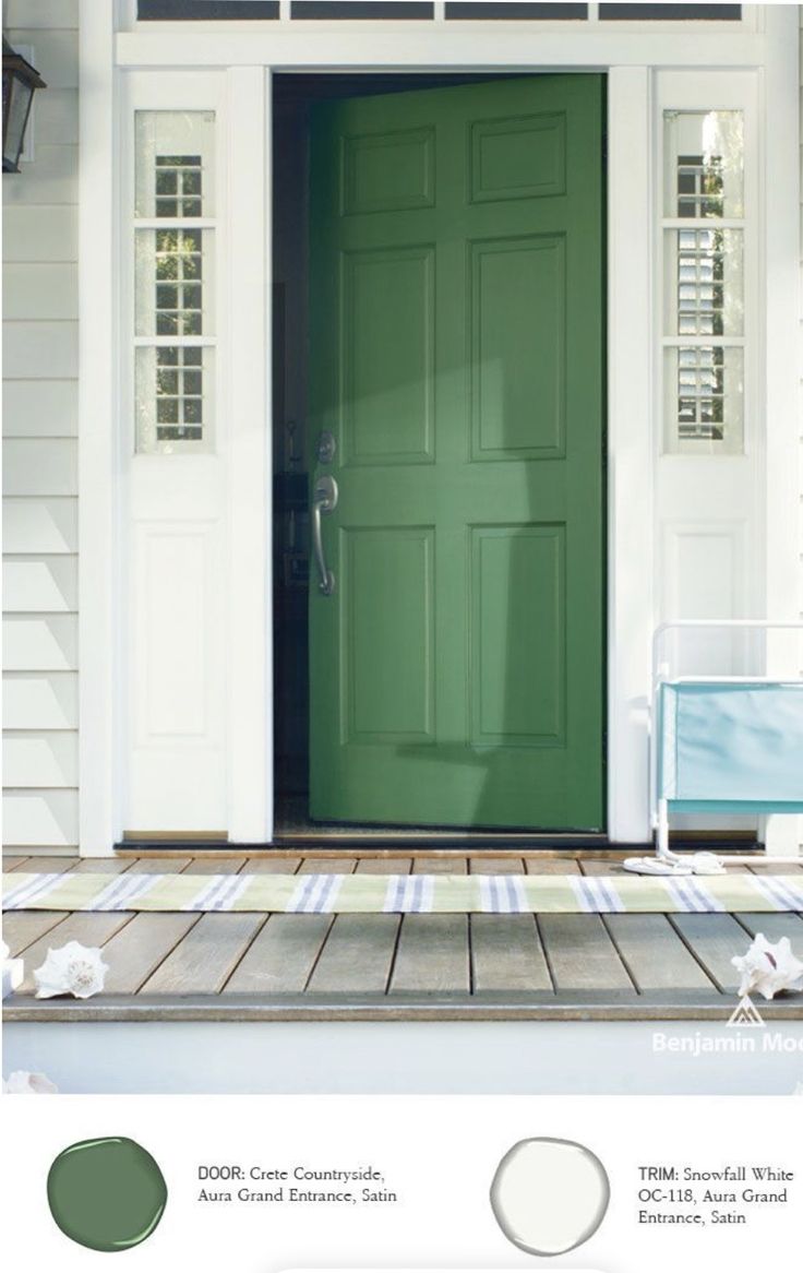 a green front door on a white house with wood flooring and two lights above it