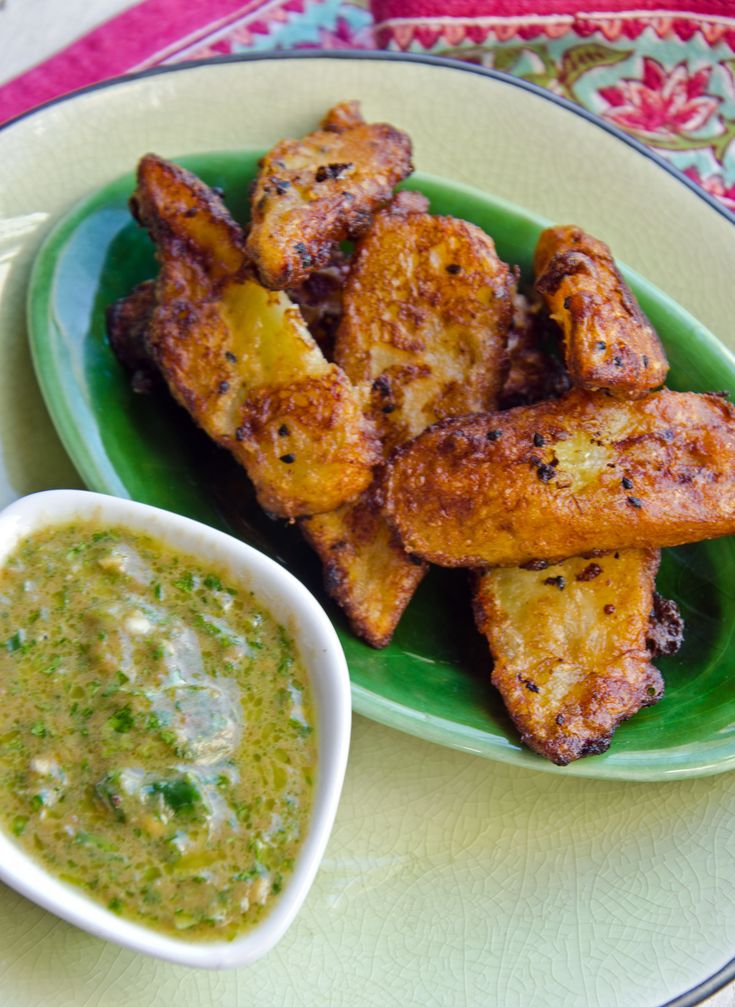 a green plate topped with chicken wings next to a bowl of dipping sauce